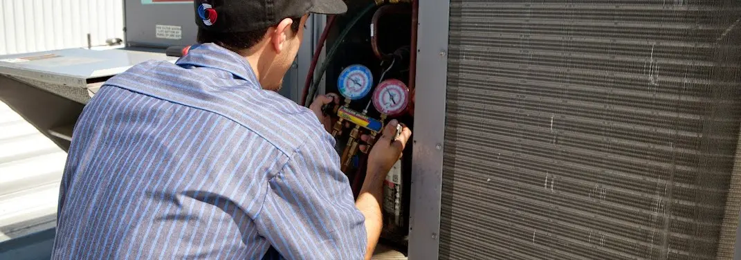 HVAC technician servicing a condenser unit in Buffalo