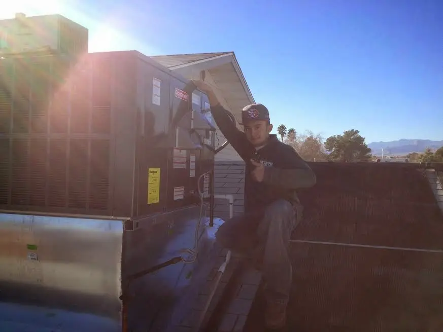 HVAC technician performing AC Tune-Up on a rooftop unit in Buffalo